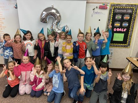 Mrs. Robertts' class celebrating "twos" day with party hats and twos on their fingers