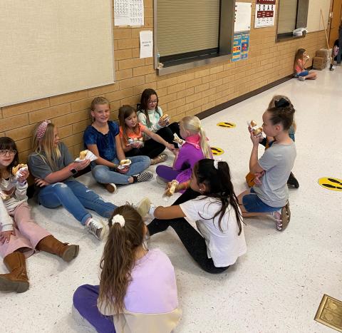Group of girls sitting on the floor eating donuts