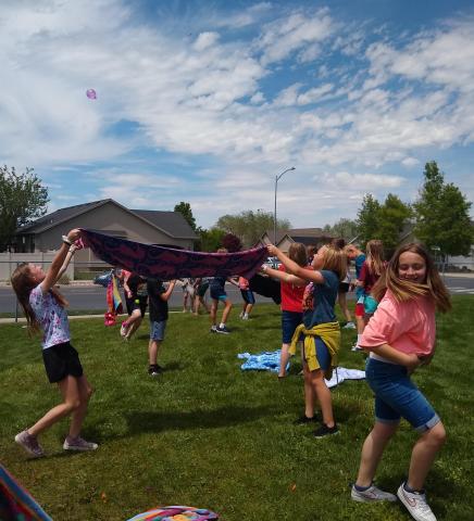Boys and girls tossing water balloons with towels during field day.