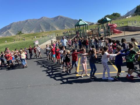 Rees students outside playing rock, paper, scissors train all together