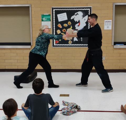 Mrs. Rawle punching a board held by the karate instructor