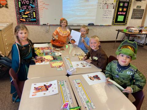Five second grade students doing a fun Halloween activity at their desks 