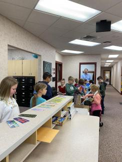 Students choosing bookmarks, books, and prizes with Mr. Cook