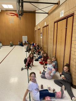 Rees Boys and girls sitting on the gym floor eating root beer floats. 