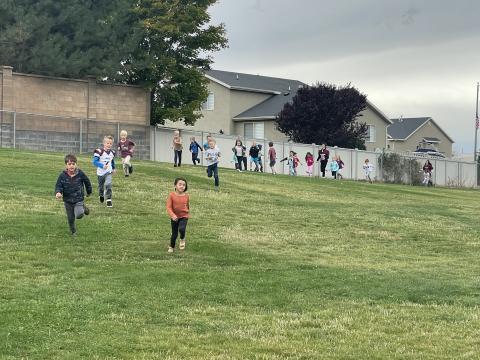 MMHS football players running outside with 1st grade, Ms. Phillips class