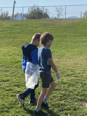 Two boys walking and picking up trash
