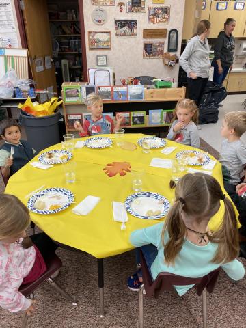Kindergarten students eating and parent volunteers helping