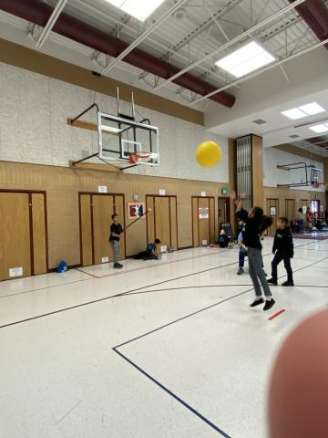 Students trying to make a basket with big ball