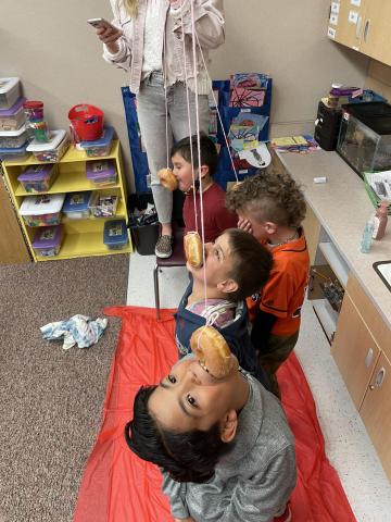 2nd grade boys eating donuts hanging from a string