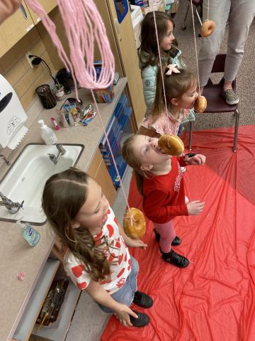 2nd grade girls eating donuts from a string