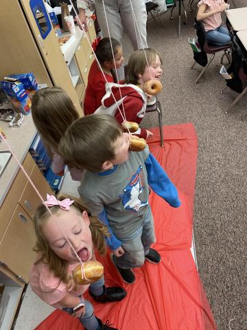 2nd grade girls and boys trying to eat donuts from a string
