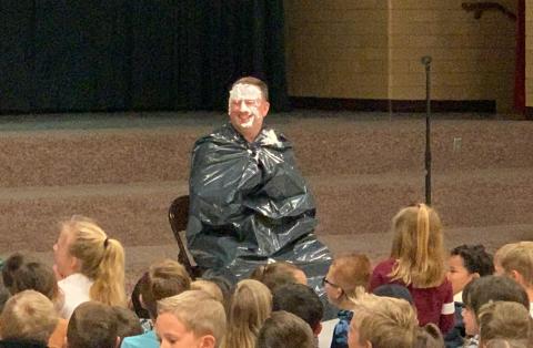 Mr. Gull sitting in front of students with "pie" on his face. 