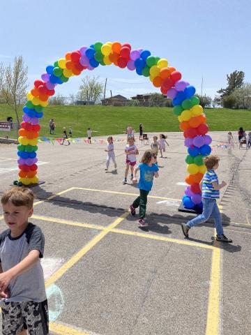 A few Rees students finishing the fun run race, running through the balloon arch