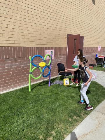 Rees girl playing frisbee toss game outside during the reading carnival