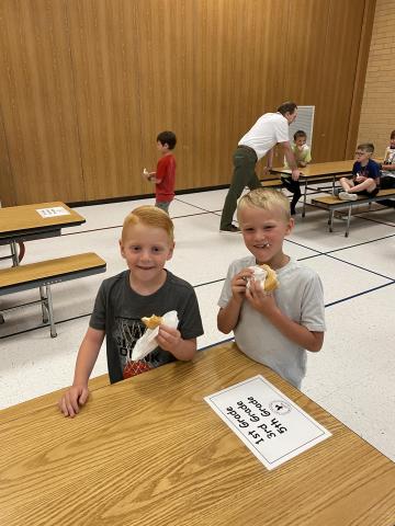 Two boys eating donuts in the gym at the donut party