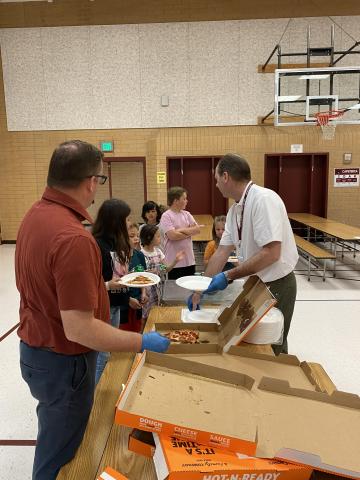 Mr. Gull and Mr. Cook serving pizza to Rees students during the pizza party. 