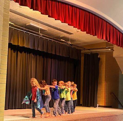 Boys and girls dancing in a line at their kindergarten graduation