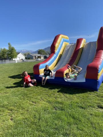 Students laughing as they get to the end of the slide at the bounce house
