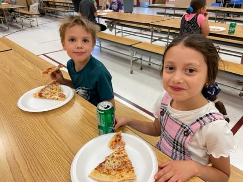 Two Rees first graders eating pizza and soda together at the party 