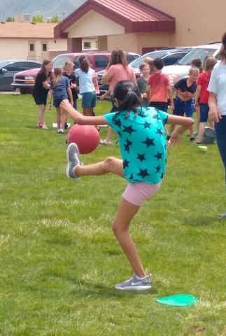 Girl kicking red ball during 4th grade kickball game