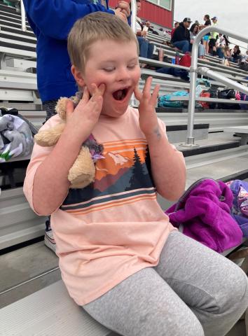 One Rees boy smiling big as he waits during the track meet