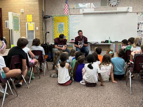 MMHS Football players reading to Miss Putnam's second grade students. 