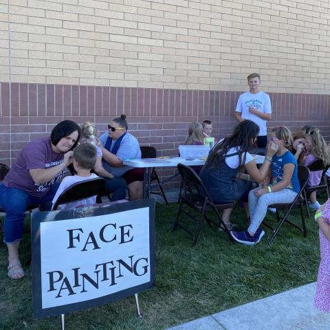 Children getting face painted by 2nd grade teachers