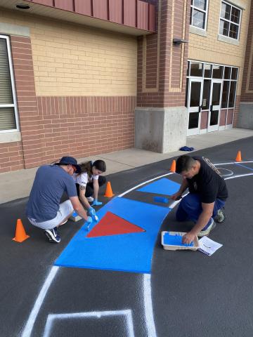 United Way volunteers painting the shape circle outside on the blacktop