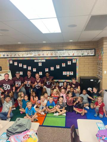 MMHS football players posing with Mrs. Coley's first grade students in her classroom