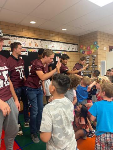 MMHS football players giving Mrs. Coley's first grade students high five. 