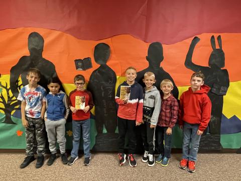 Rees 4th Grade students with the book Bud Not Buddy standing in front of the characters they made from the book