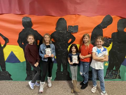 Rees 4th Grade students with the book A Night Divided standing in front of the characters they made from the book