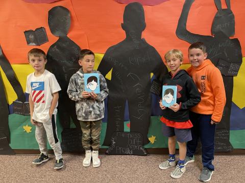 Rees 4th Grade students with the book Wonder standing in front of the characters they made from the book