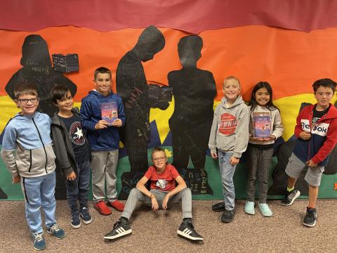 Rees 4th Grade students with the book When Stars are Scattered standing in front of the characters they made from the book