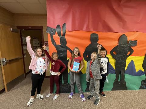 Rees 4th Grade students with the book club book standing in front of the characters they made from the book