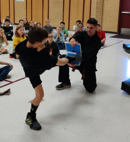 Rees boy kicking a board held by karate instructor
