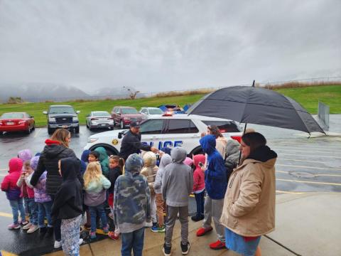 Rees students standing in from of police car and  learning from Officer Smith about being safe. 