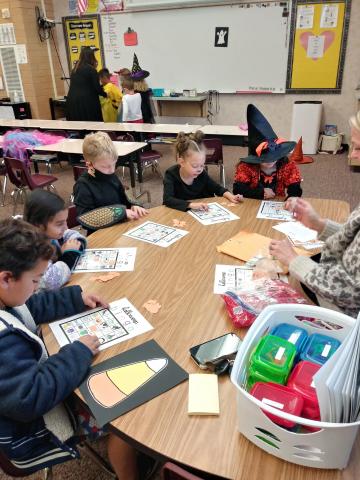 A Group of first grade students sitting at a table doing a Halloween activity during their party