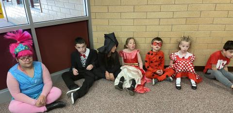 Students in Mrs. Hirst's EEC class sitting down by the wall watching the Halloween parade