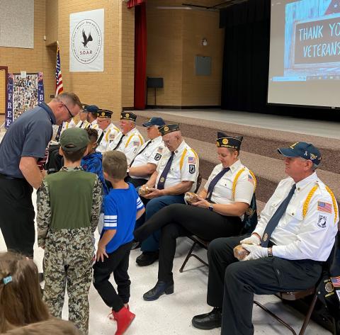 Mr. Gull and three Rees students giving the Veterans some bread after the assembly 