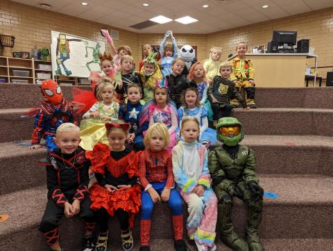 Mrs. Bodily's AM Kindergarten class sitting on the stairs dressed in their Halloween costumes. 