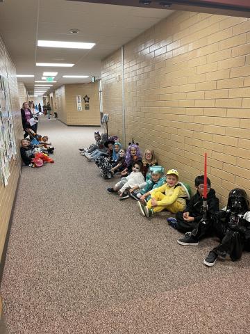 Second graders sitting in the hall wearing their costumes watching the parade