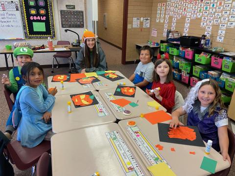 A mom helper and five students doing a Halloween art project during a class party