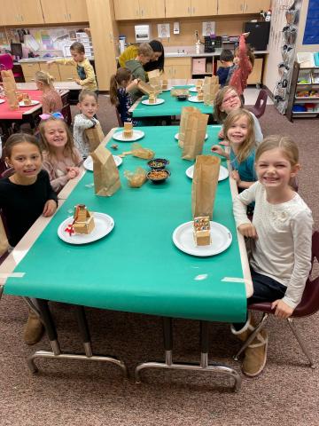 Girls and boys smiling as they decorate their candy houses in 1st grade