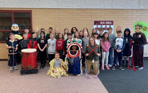 Mrs. Luke and her 4th grade students with dragon, drums, and people dressed up for Lunar New Year