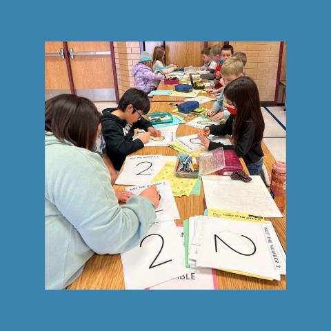 Students working on twos activities sitting at a table in a group.