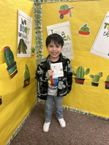 kindergarten boy holding a SOAR slip after passing Heggerty with 100% score
