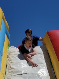 Boy sliding down the bounce house slide with a smile on his face. 