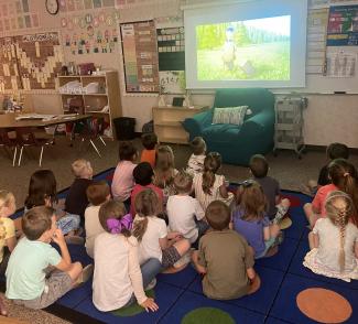 Kindergarten students watching a screen and learning about setting goals. 