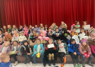 Mrs. Anna Memmott's class with other students sitting on the stairs in the gym during the egg drop. 